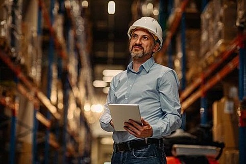 Man wearing a safety hat in the NSJ Wholesale warehouse as supplier orders are packed for distribution